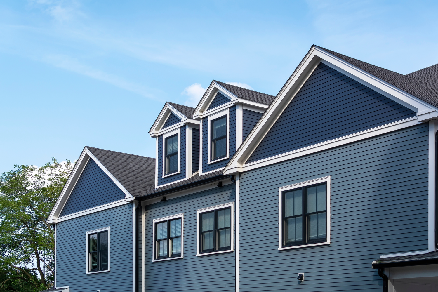 Two workers installing vinyl siding on a residential building with single-hung and double-hung windows. | S&S Remodeling