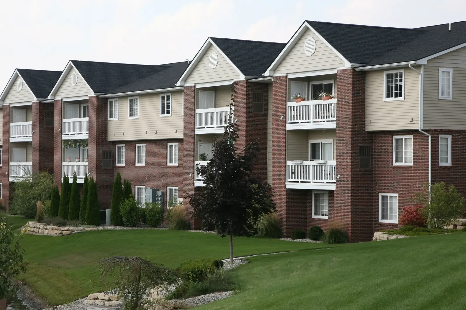 A picture of a multi-family building with new asphalt roof and installed windows. | S&S Remodeling